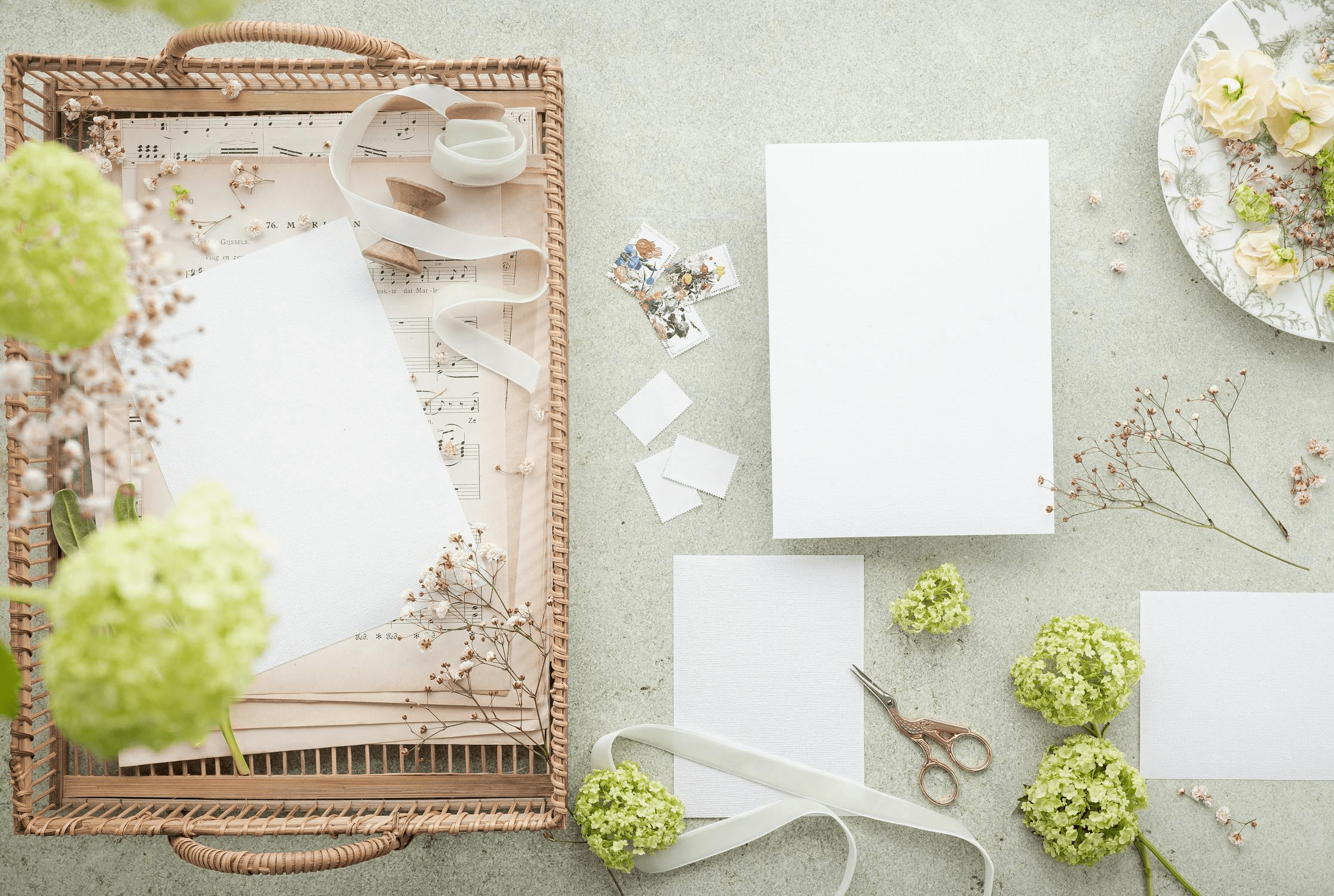 Scrapbook supplies on a table. The supplies include paper, scissors, ribbon and stamps.