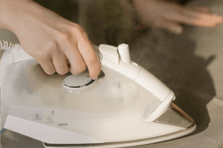 woman ironing fabric using iron on an ironing board